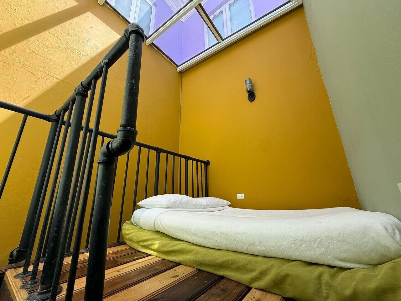 A room with a bed, a skylight, and a staircase.