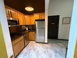 A kitchen with wooden cabinets, stainless steel appliances, and a tiled floor. - Elegant San Juan Loft for 8 • The Mezzanine (San Juan de Puerto Rico)