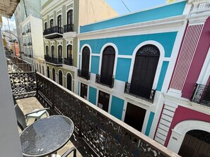 A balcony with a wrought iron railing, a round table, and chairs. - Elegant San Juan Loft for 8 • The Mezzanine (San Juan de Puerto Rico)