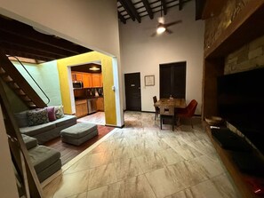 A spacious living area with a staircase, a dining table, and a television. - Elegant San Juan Loft for 8 • The Mezzanine (San Juan de Puerto Rico)