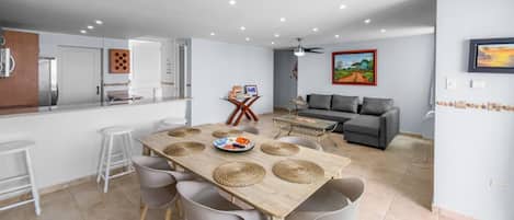 A modern kitchen with a dining area, grey furniture, and a grey sofa in the living room.