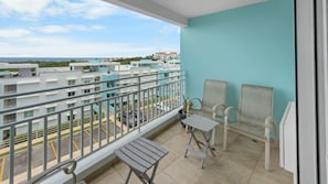 A balcony with two chairs, a small table, and a view of a residential area. - Hillside Village Hideaway | Sleeps 8 Comfortably (Mameyes II)