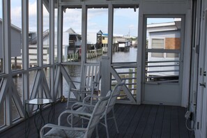 En overdækket terrasse med hvide gelændere, et bord og to stole.