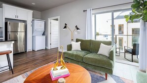 Un appartement moderne doté d’une cuisine, d’un canapé vert, d’une table basse en bois et d’un balcon avec vue.