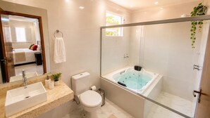 A modern bathroom with a glass-enclosed shower, a large bathtub, a toilet, and a sink.