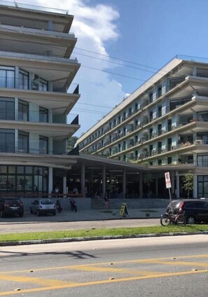 Ein mehrstöckiges Hotel mit überdachter Eingangspartie und Parkplatz.