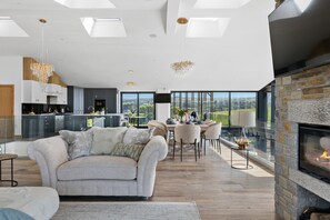 Un vaste espace de vie comprenant une cheminée, un canapé et une table à manger avec des chaises.