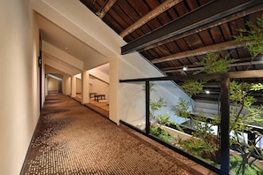 A modern interior with a wooden ceiling, a long hallway, and a view of greenery outside. - yonghe yard hotel (Beijing)