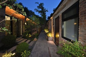 A brick building with large windows and a paved pathway. - yonghe yard hotel (Beijing)