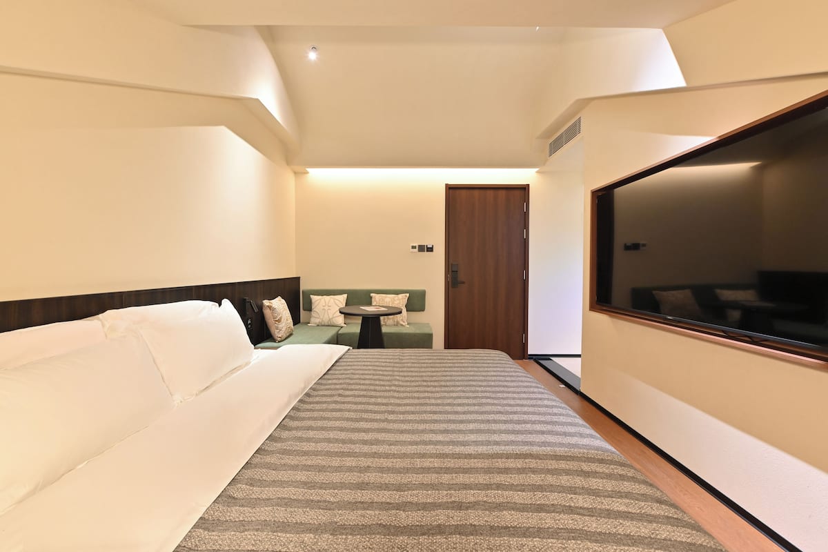 Una habitación de hotel con una cama, un sofá, una mesita y un televisor.