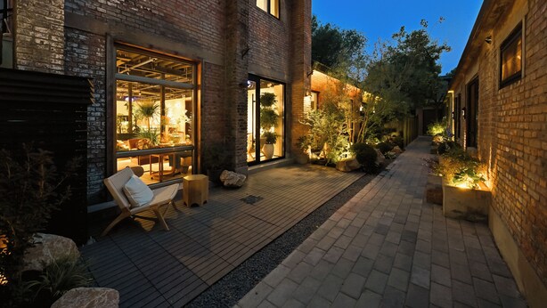 Un edificio de ladrillo con un patio, mobiliario exterior y plantas en macetas.