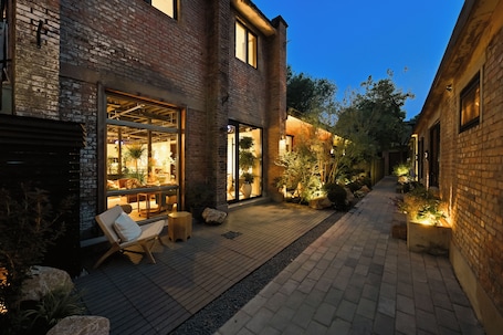 A brick building with a patio area, outdoor seating, and potted plants.. yonghe yard hotel