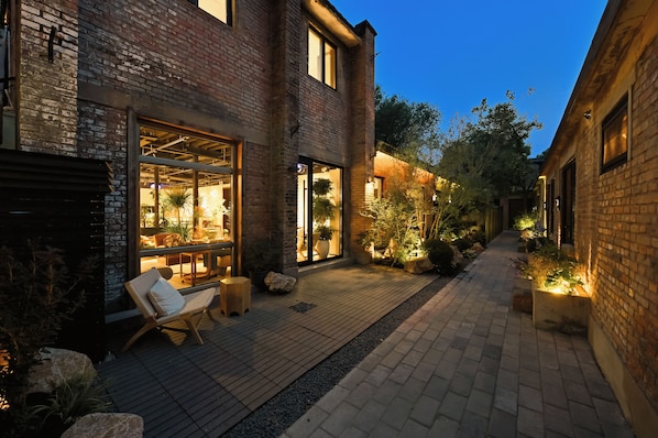 A brick building with a patio area, outdoor seating, and potted plants.