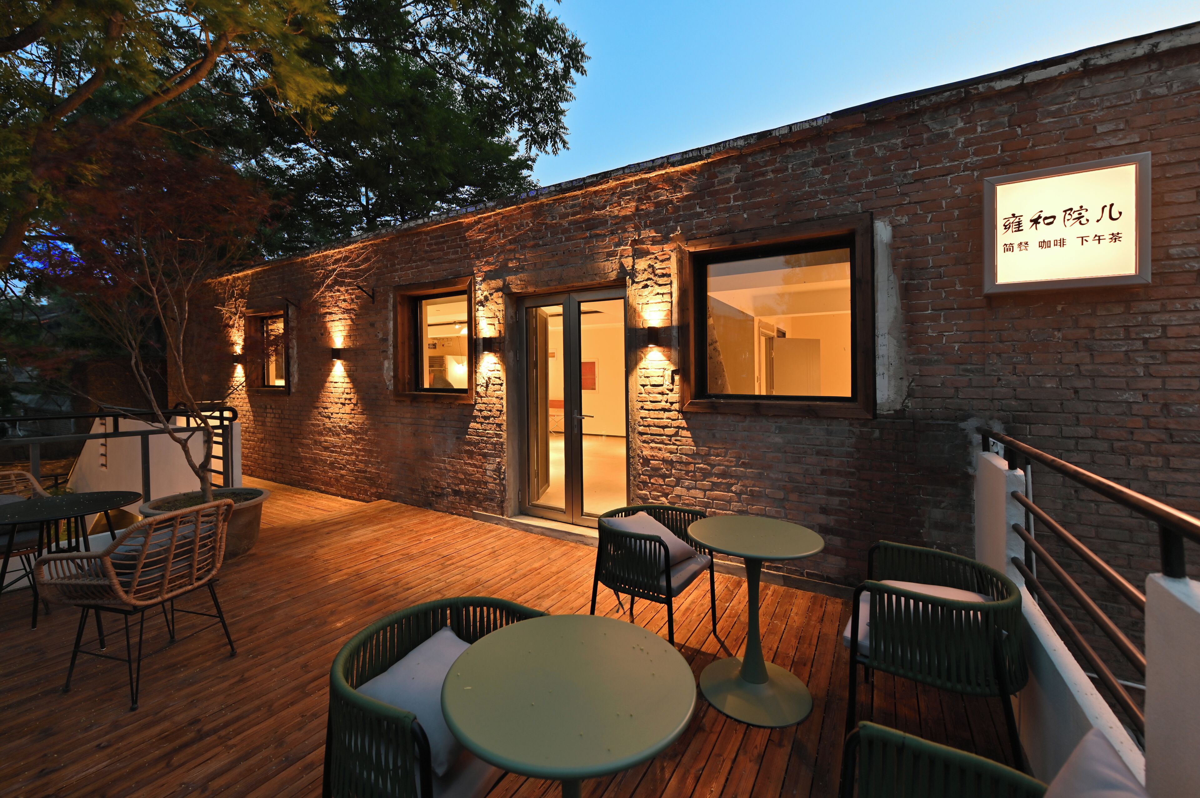 An outdoor patio with wooden flooring, wicker chairs, and tables.