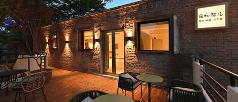 An outdoor patio with wooden flooring, wicker chairs, and tables.