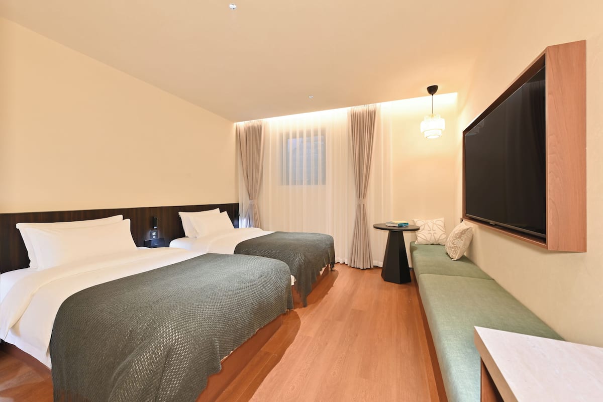 Una habitación de hotel con dos camas, un sofá, un televisor y una mesita.