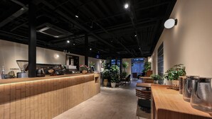 Un interior moderno con una recepción, zona de estar y plantas en macetas.