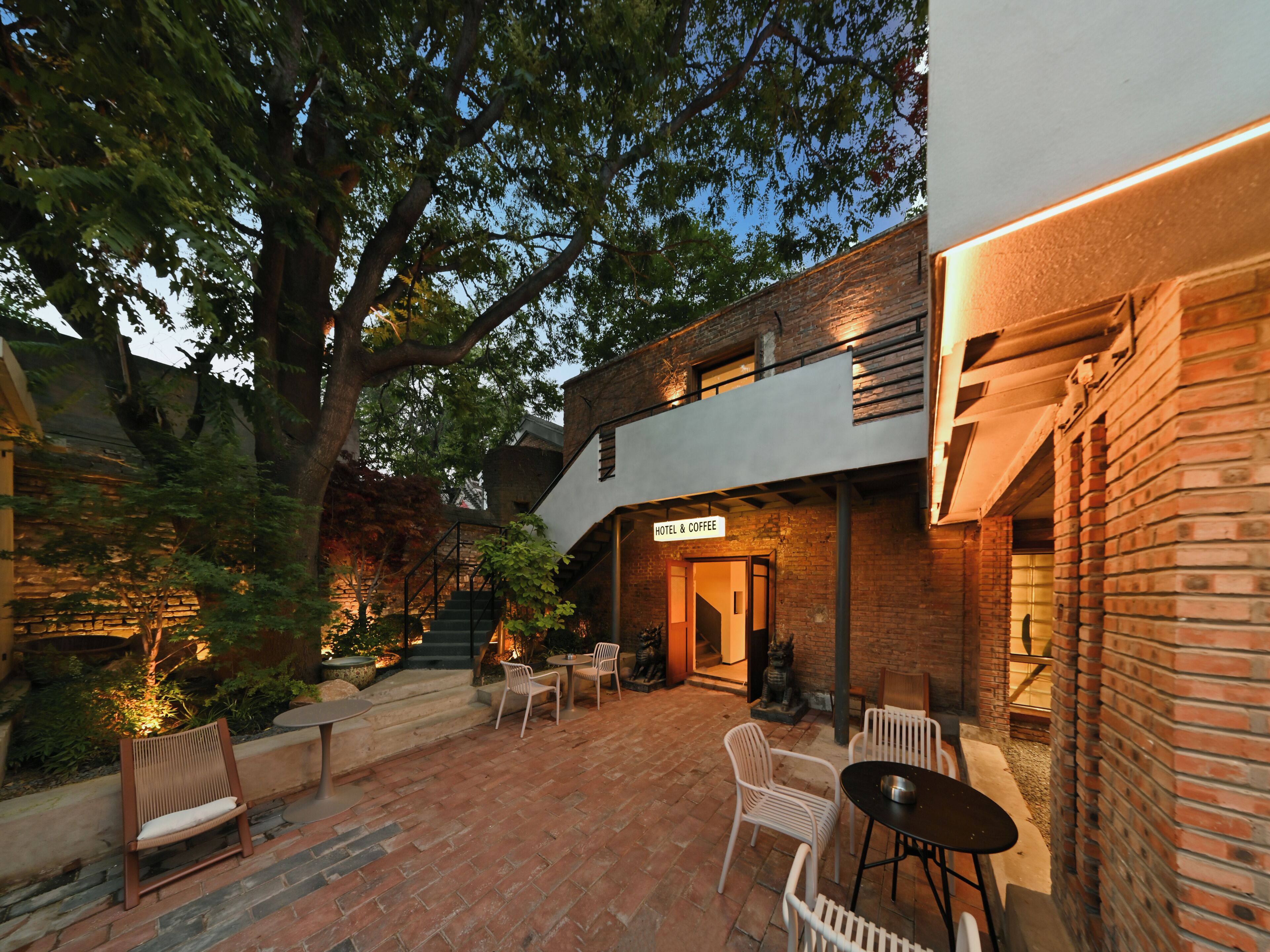 A hotel with a sign reading 'HOTEL & COFFEE,' outdoor seating, and a brick exterior.