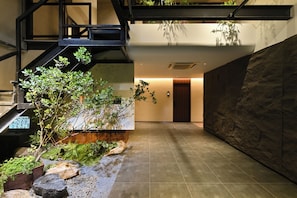 A modern interior with a staircase, indoor plants, and a stone wall. - yonghe yard hotel (Beijing)