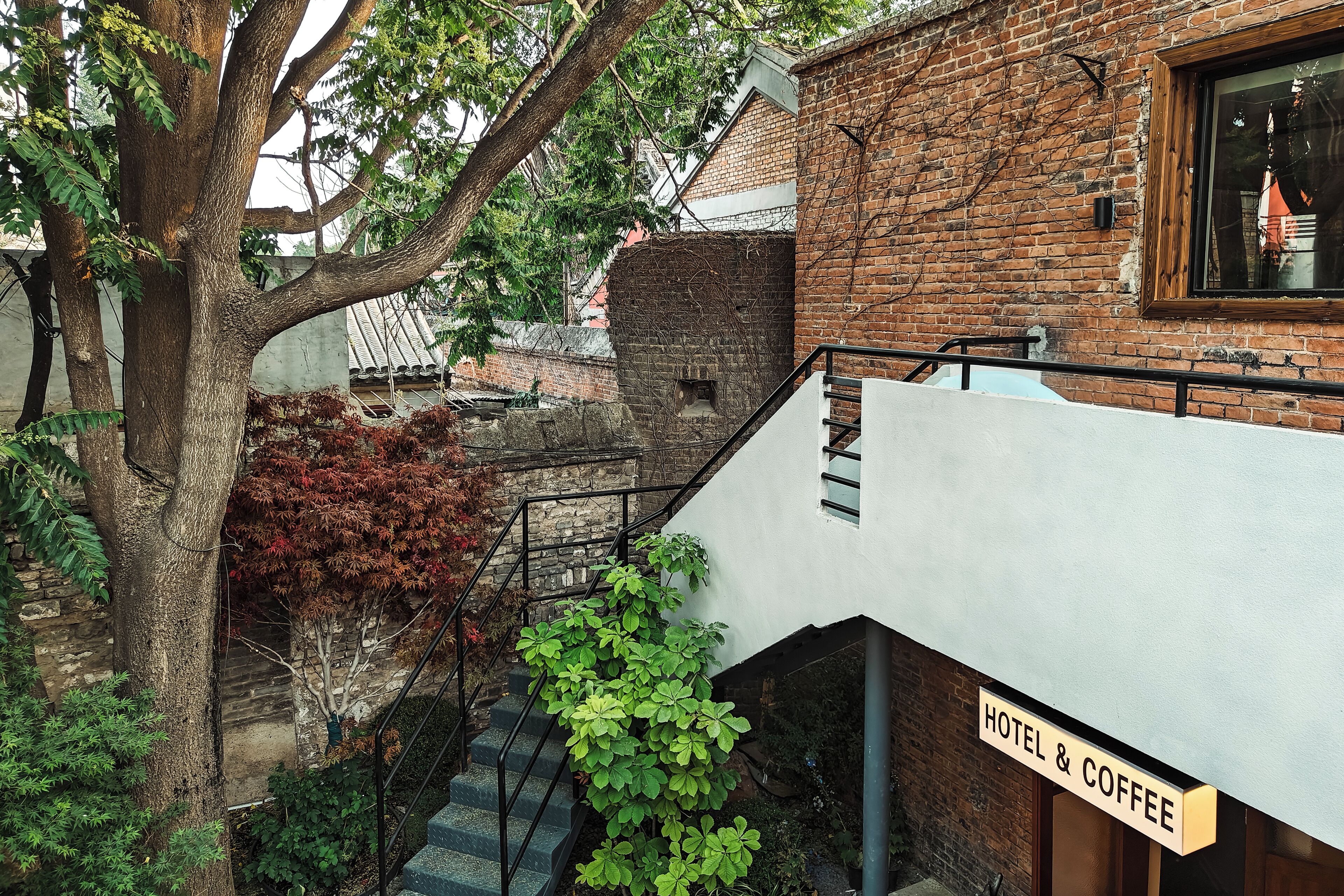 A hotel with a brick facade, a staircase, and a sign indicating it offers hotel and coffee services.