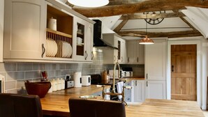 Una cocina con vigas de madera, armarios blancos y una mesa de comedor de madera con sillas.