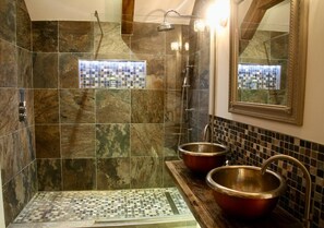 A bathroom with a shower, two sinks with copper basins, and a mosaic tile wall. - Cotswolds Grade II Listed Barn +underfloor heating (Little Rissington)