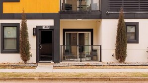 A modern multi-story building with balconies, a visible entrance, and a number '1401' on the facade. - H3 Spacious & Urban Modern Condo - Great Location! (Oklahoma City)