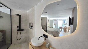 Ein modernes Badezimmer mit großem Spiegel, einem runden Waschbecken und einer Dusche.