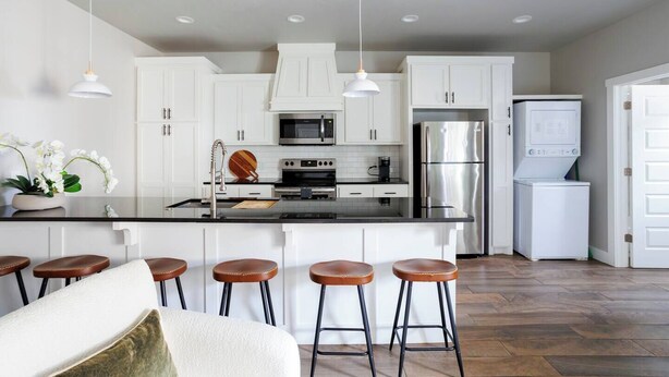 A modern kitchen with white cabinets, stainless steel appliances, and a central island with stools. - H4 Spacious & Urban Modern Condo - Great Location! (Oklahoma City)