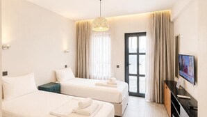 Habitación de hotel con dos camas, televisión, escritorio y ventana con cortinas.