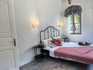 Ett sovrum med en säng, sängbord, ett fönster med gardiner och en dörr.