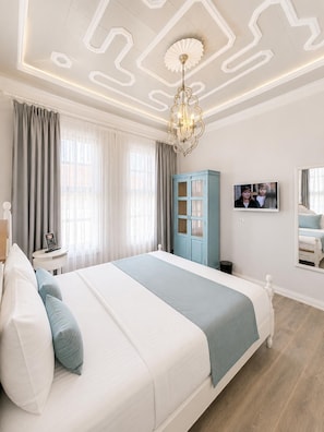 A modern hotel room with a large bed, a TV, a wardrobe, and a chandelier. - Alada Saphire Bozcaada (Bozcaada)