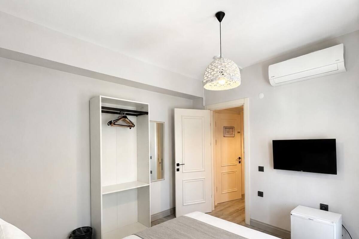 Una habitación de hotel moderna con una cama, un armario, un televisor y un equipo de aire acondicionado.