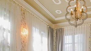 Un dormitorio con cama, candelabro, cortinas y una bandeja con frutas y vasos.