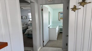 Ein Flur, der in ein Schlafzimmer mit Bett, Schreibtisch und Stuhl führt.