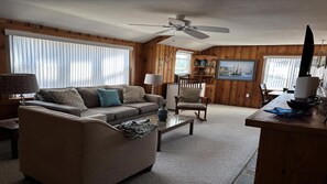 Ein Wohnzimmer mit Sofa, Sessel, Couchtisch und Deckenventilator.