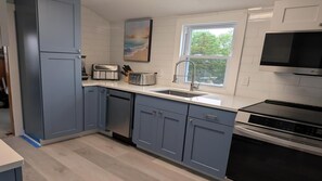 Eine moderne Küche mit blauen Schränken, einer weißen Arbeitsplatte, einem Toaster, einer Spüle und einem Herd.