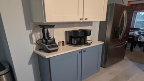 Eine Küche mit Mixer, Kaffeemaschine und Kühlschrank.