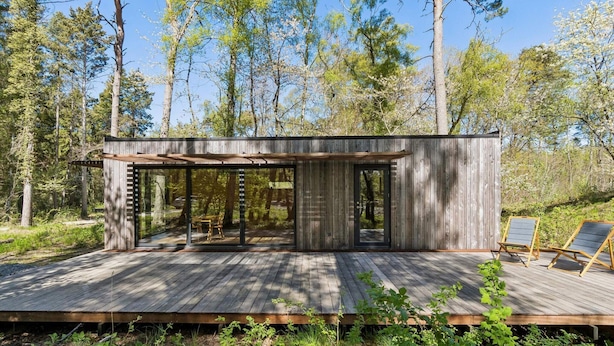 A wooden cabin with a deck, large windows, and a dining area. - 4 Star Holiday Home in Hasle (Hasle)