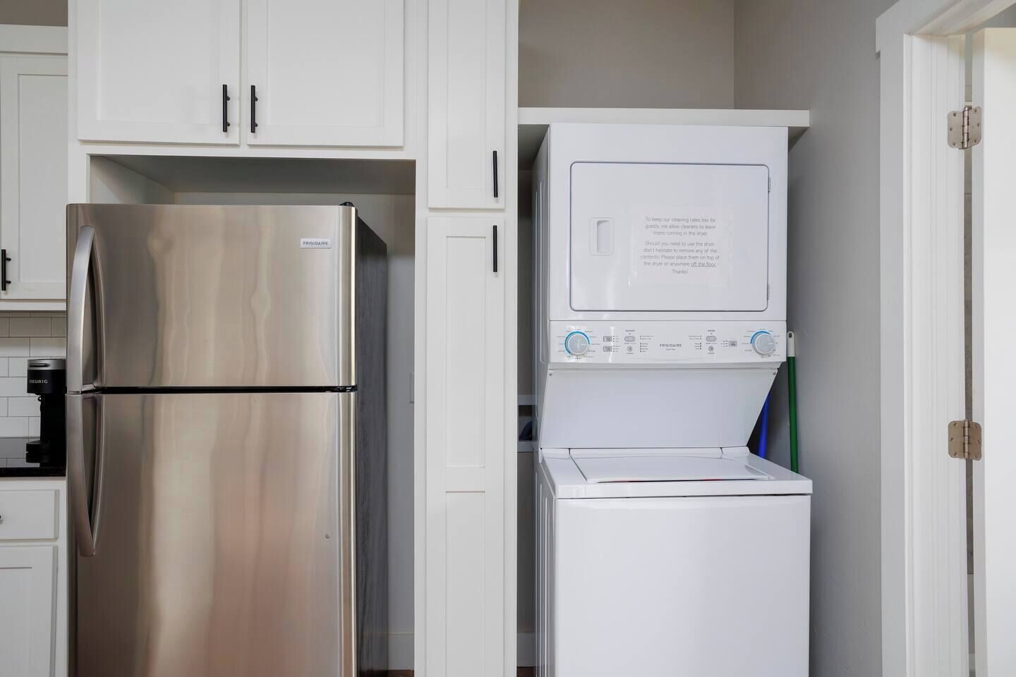 A compact kitchen with a stainless steel refrigerator and a built-in washer-dryer unit.