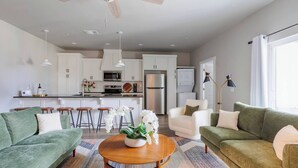 Una sala de estar moderna con un sofá verde, una mesa de centro redonda de madera y una orquídea blanca como centro de mesa.
