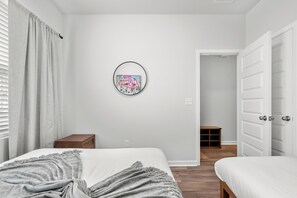 Una camera da letto con un letto, un comodino, un quadro appeso al muro e una porta che conduce a un'altra stanza.
