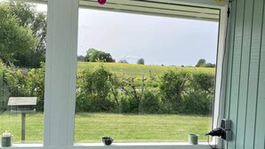 A room with a large window, a bench, and a view of a green field.
