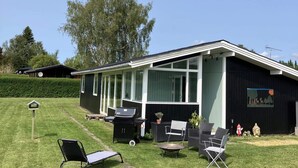 A modern house with a covered patio, outdoor furniture, and a barbecue setup.
