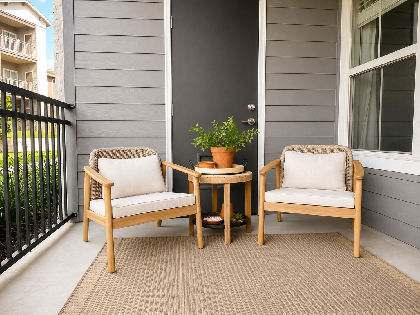 A balcony with two wicker chairs, a small table, and a potted plant.