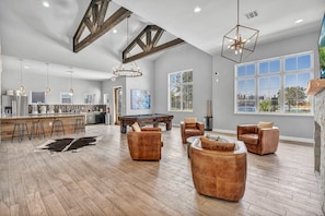 A spacious living area with a pool table, leather sofas, and a bar area with stools.
