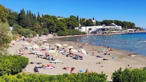 A beach with sun loungers, umbrellas, and people swimming. - Large 3BR Apartment in the Center & Sand Beach 5BD (Split)