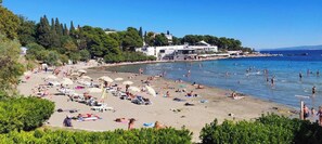 Ein Strand mit Liegestühlen, Sonnenschirmen und badenden Personen.