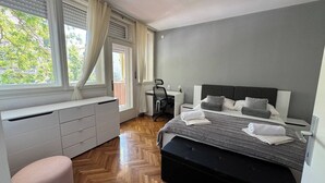 A bedroom with a bed, a desk, a chair, a window with curtains, and a radiator. - Large 3BR Apartment in the Center & Sand Beach 5BD (Split)
