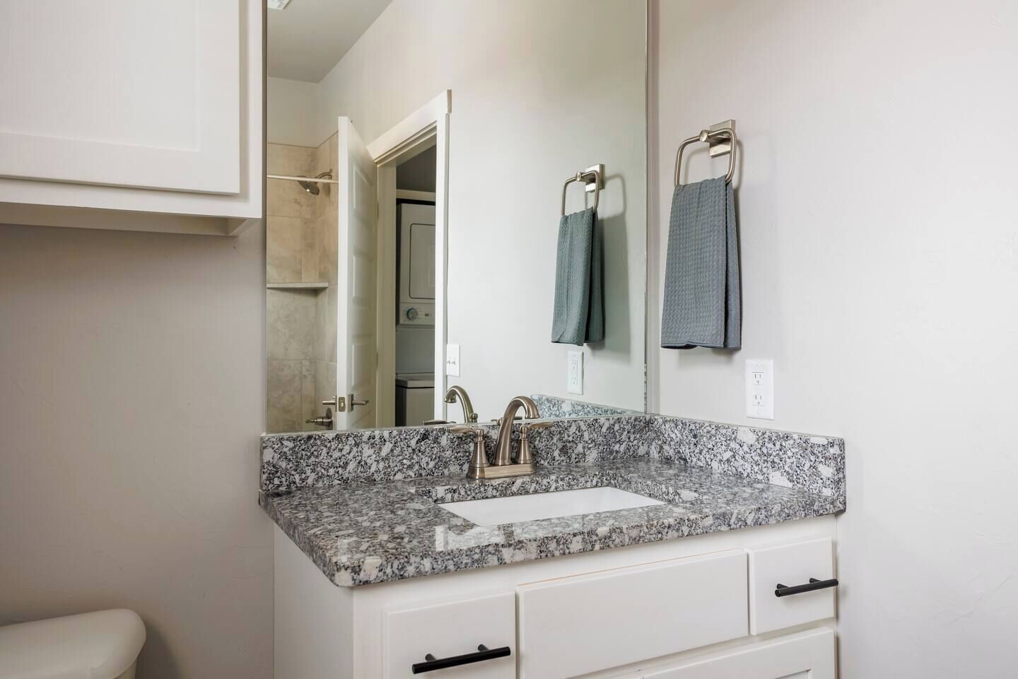 A bathroom with a granite countertop, a sink, a mirror, and a towel rack.